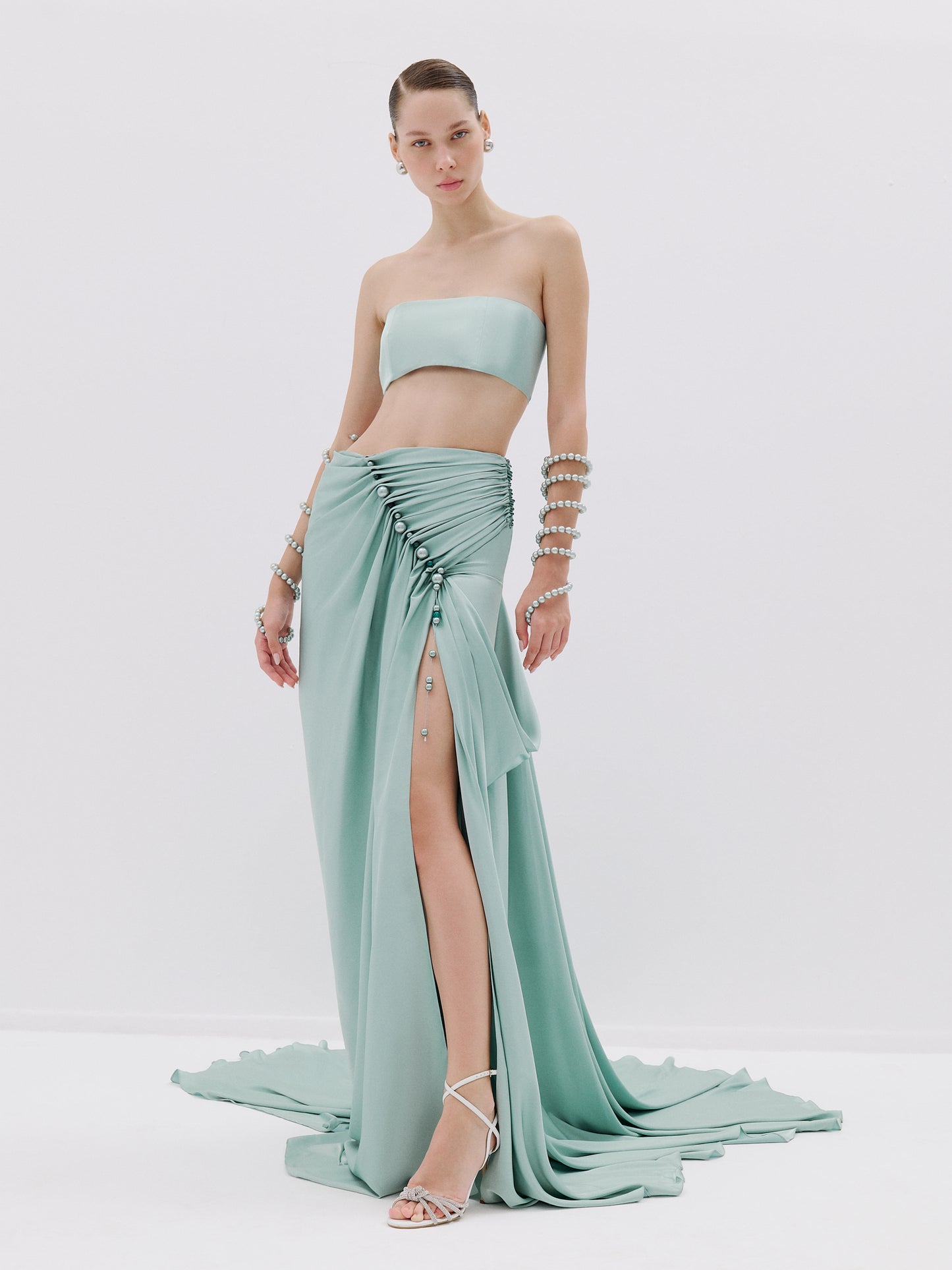 Draped skirt with pearl buttons and high slit.